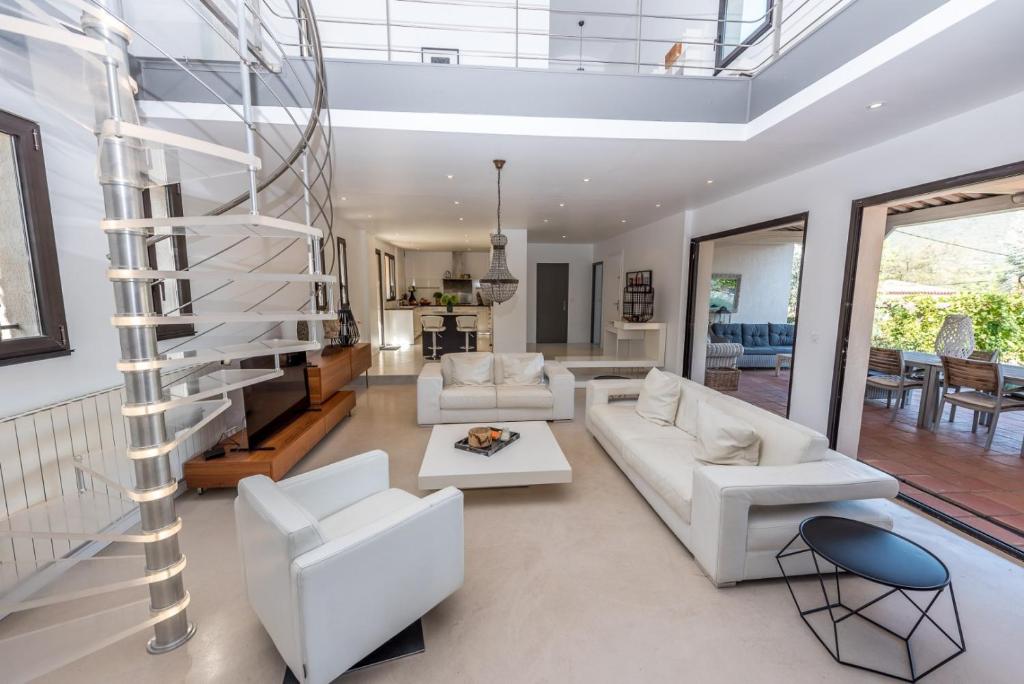 d'un salon avec un mobilier blanc et un escalier en colimaçon. dans l'établissement Villa Le Bastidou, au Plan-de-la-Tour