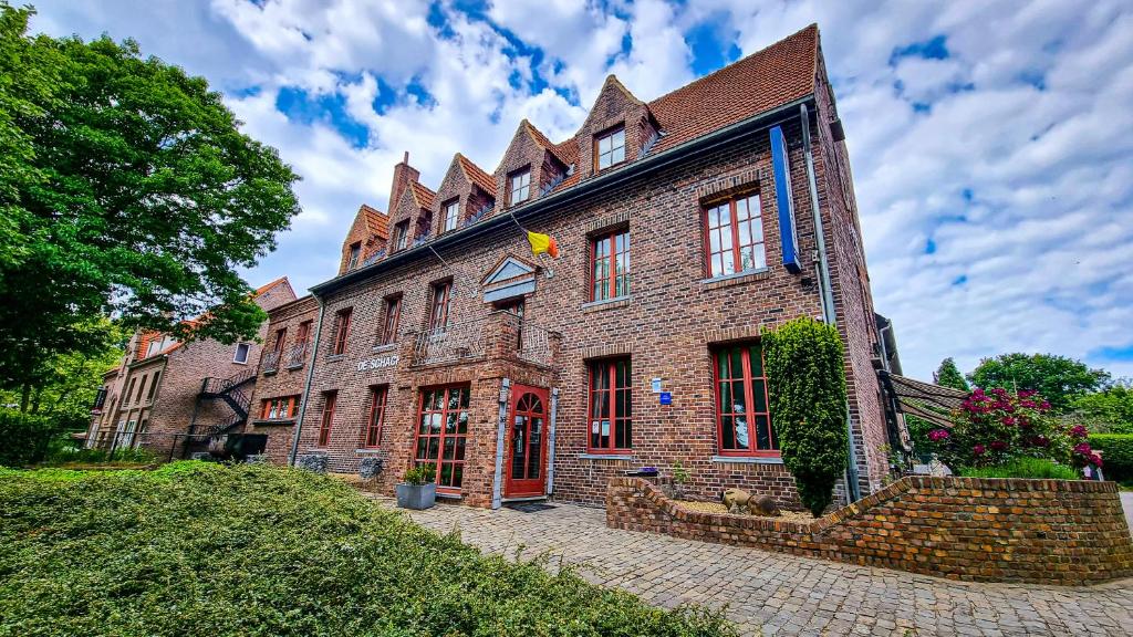 een groot bakstenen gebouw met een vlag erop bij Hotel De Schacht in Genk