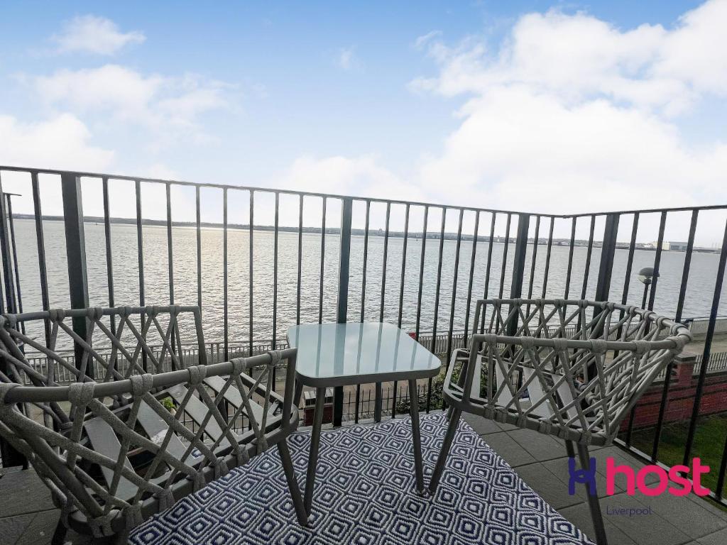 a table and chair on a balcony overlooking the water at Host Liverpool - Riverside Retreat by centre with private parking in Liverpool