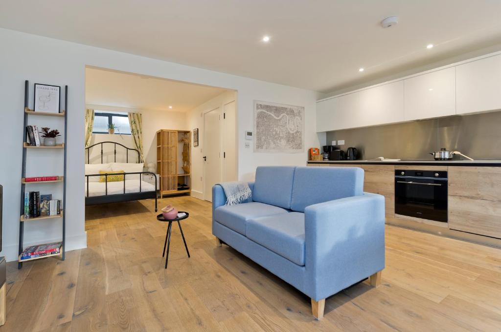 ein blaues Sofa im Wohnzimmer mit Küche in der Unterkunft Luxury one bedroom Greenwich studio apartment near Canary Wharf by UnderTheDoormat in London
