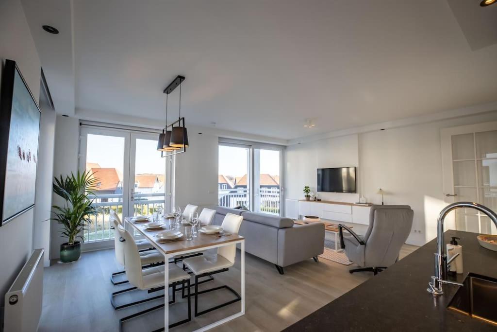 a living room with a dining table and a kitchen at Home Away, Light and Bright in Cadzand