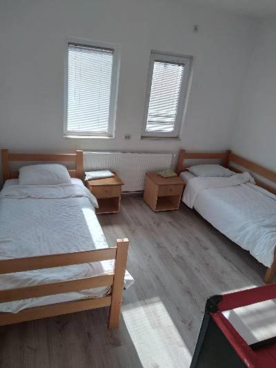 a bedroom with two beds and two windows at VILLA SIMKA in Kočani