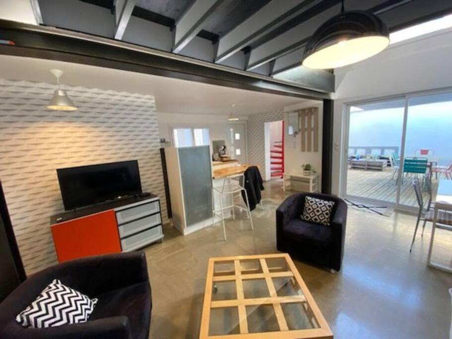 a living room with a tv and chairs and a table at Maison duplex avec terrasse proche de la gare SNCF in Clermont-Ferrand