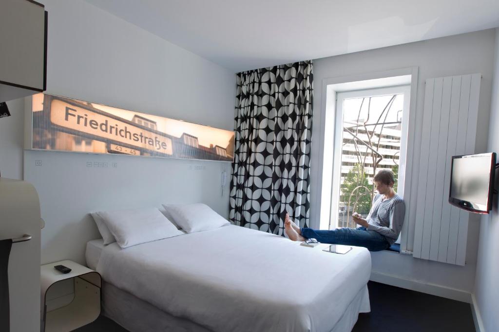 Una donna seduta sul davanzale di una finestra in una stanza d'albergo di Hotel Gat Point Charlie a Berlino