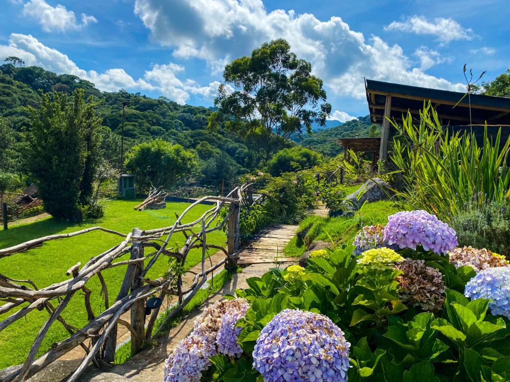 un jardín con flores púrpuras y una valla en Pousada Olivier da Montanha - Recanto das Águas, en Santo Antônio do Pinhal