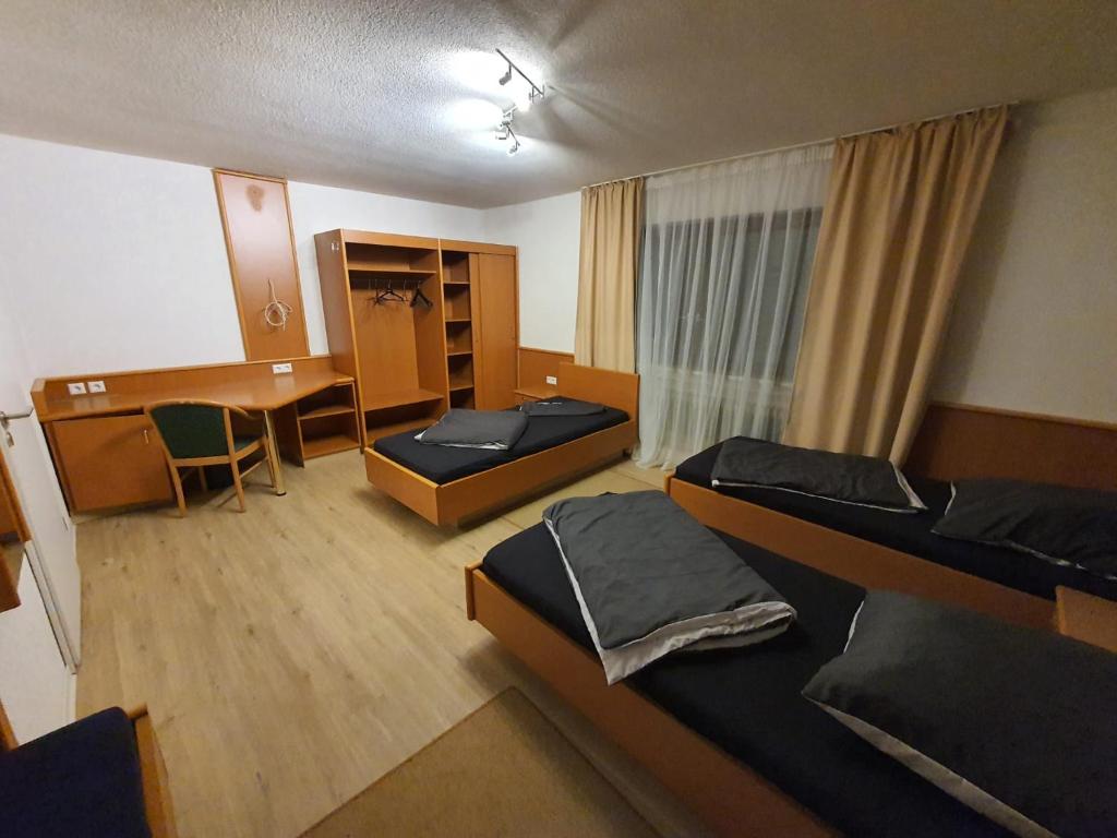 a room with two beds and a table and a desk at Monteurzimmermit Gemeinschafst Bad-Küche- AM RHEIN 