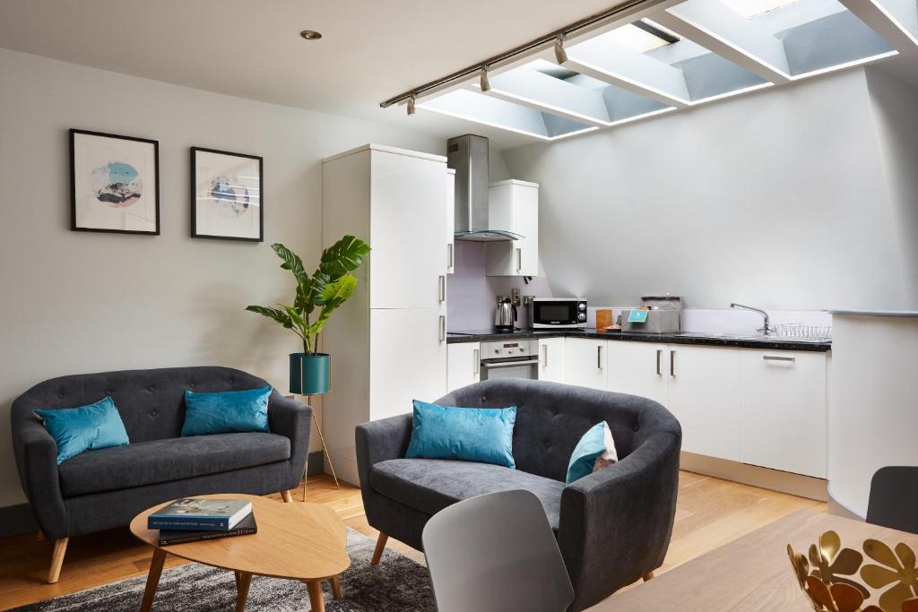 a living room with two couches and a kitchen at Holborn by Viridian Apartments in London