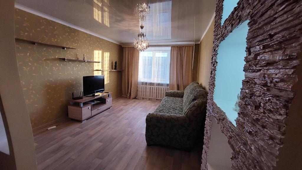 a living room with a couch and a television at 2 комнатная квартира in Shchūchīnsk