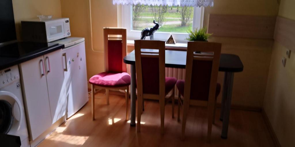 a kitchen with a table and four chairs and a kitchen with a window at Vieno kambario butas su balkonu in Kaunas