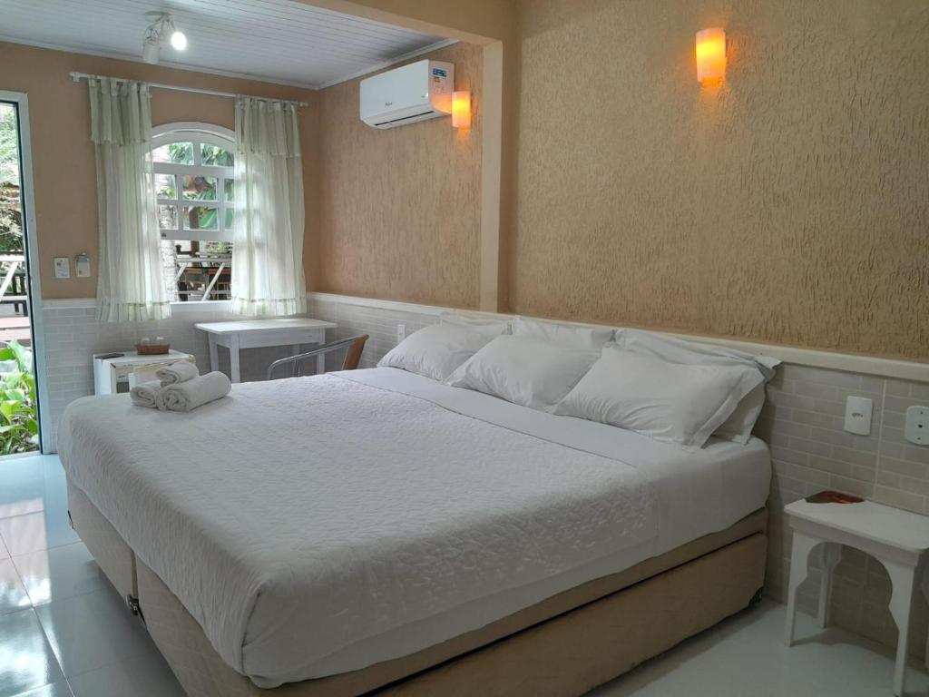 Pousada Nascente Pequena في غوابيميريم: غرفة نوم بسرير كبير مع شراشف بيضاء