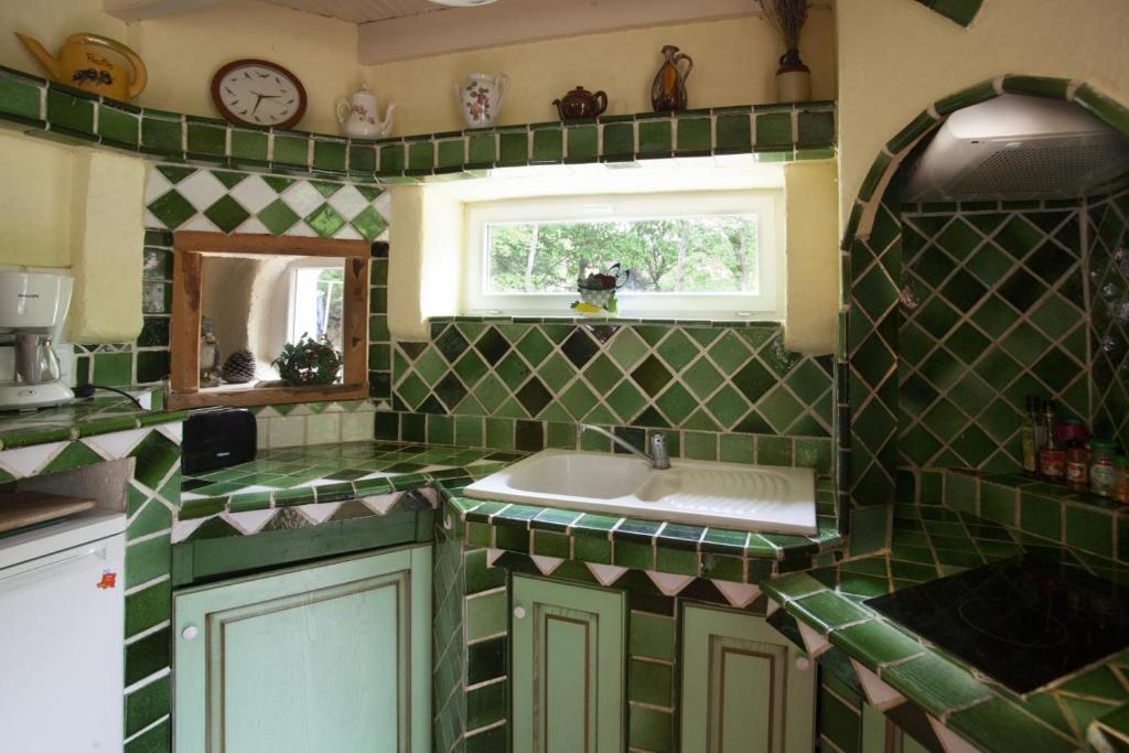a green tiled kitchen with a sink and a window at Gite au calme l'eclaircie in Régusse