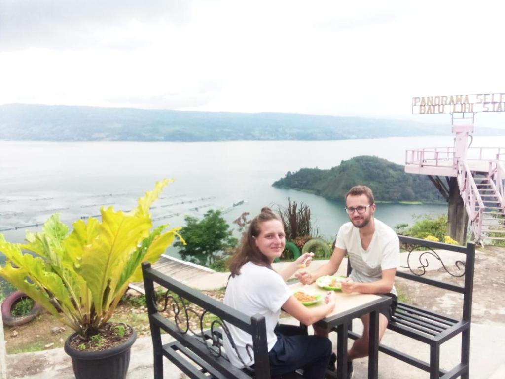 Un uomo e una donna seduti a tavola mangiando cibo di Sapo Karo Rest House a Berastagi