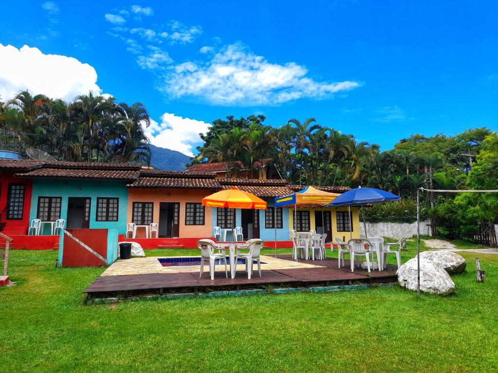 una casa con terraza con sillas y sombrillas en Chalés do Inglês, en Ilhabela