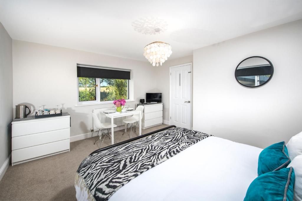a white bedroom with a zebra print bed and a desk at Stibb Hollow Farm in Great Torrington