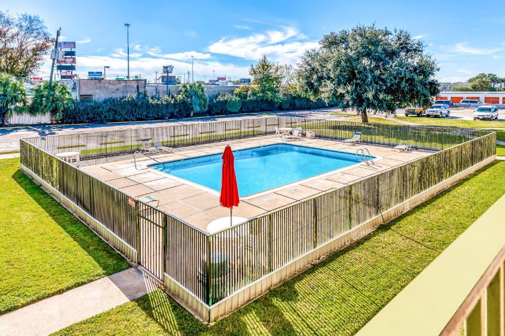 una piscina con una valla y una sombrilla roja en OYO Hotel Houston Southwest I-69, en Houston