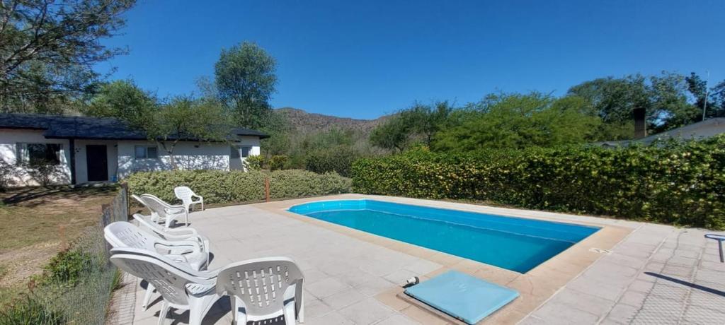 a swimming pool with a group of chairs next to it at Casa Condal in Villa General Belgrano