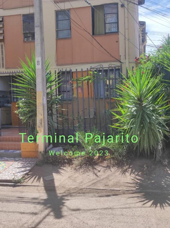 una valla frente a un edificio con palmeras en Terminal Pajarito en Santiago