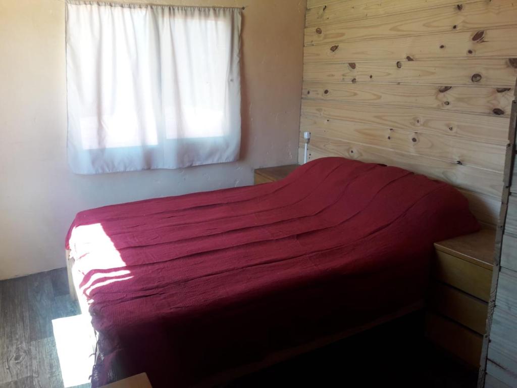 1 dormitorio con cama roja y ventana en Macrigaluma Luna, en Barra del Chuy