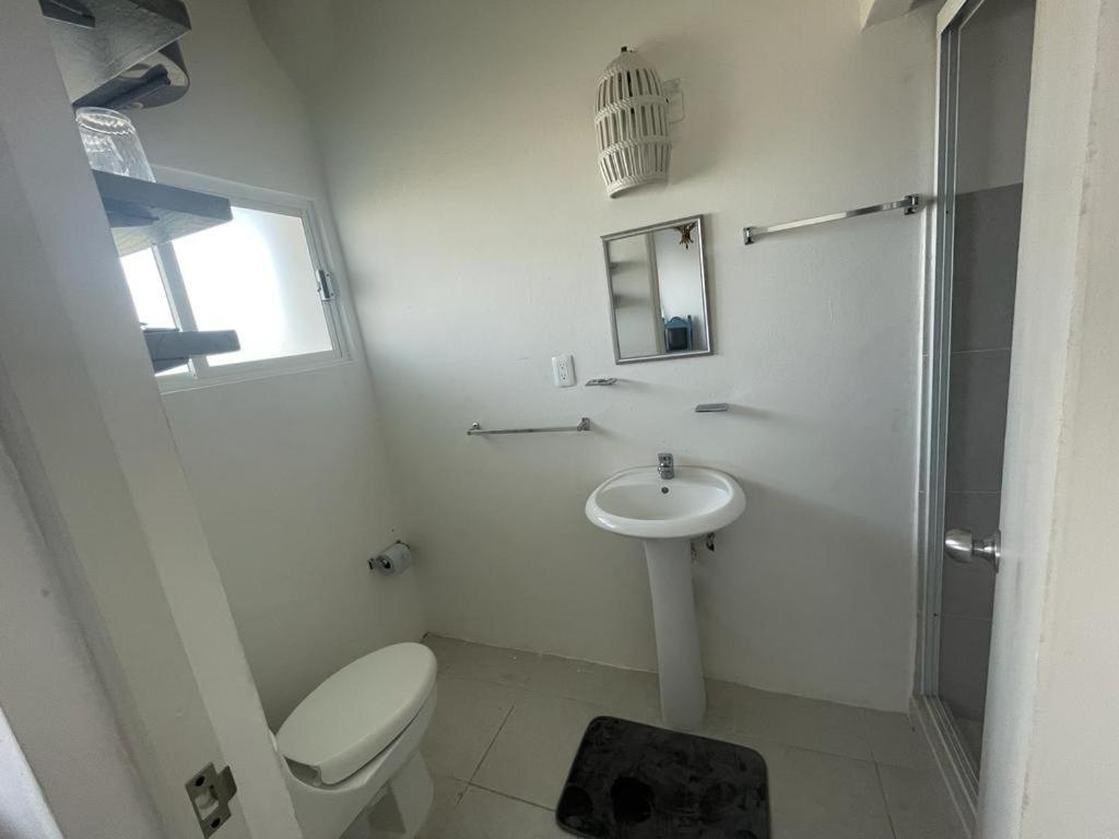 a white bathroom with a toilet and a sink at Loft 208 in Acapulco