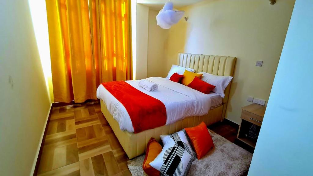 um quarto com uma cama com almofadas vermelhas e laranja em Spacious 1,2 bedroom all master ensuit with a lake view em Nakuru