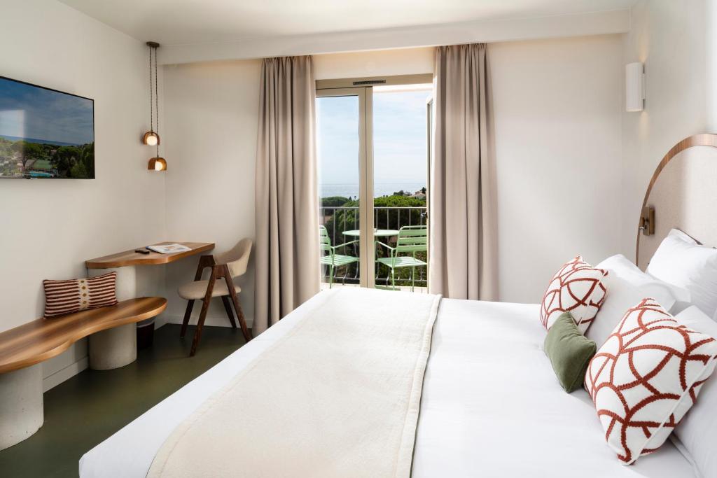 a bedroom with a large white bed and a desk at Hôtel du Parc Cavalaire sur Mer in Cavalaire-sur-Mer