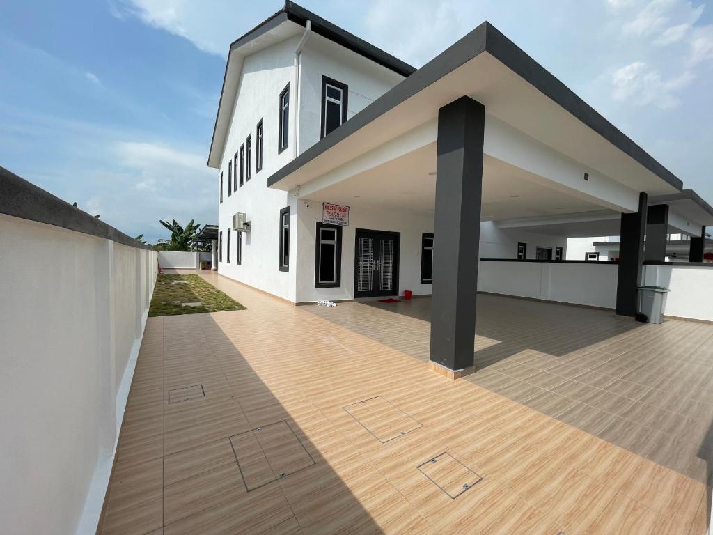 a large white house with a wooden deck at Villa homesty Port Dickson in Port Dickson