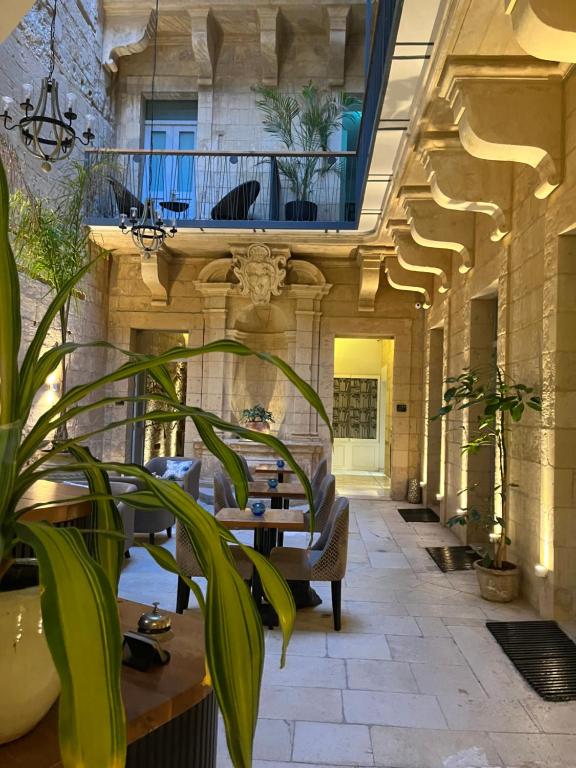 einen Flur mit Tischen und Pflanzen in einem Gebäude in der Unterkunft 66 Saint Paul's & Spa in Valletta