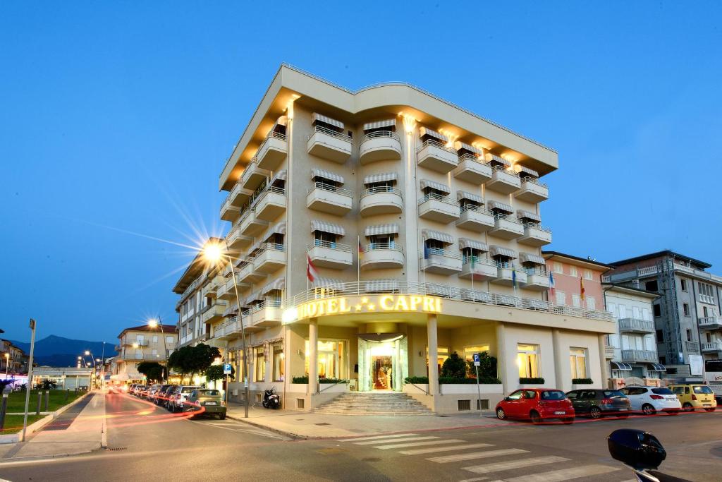 a large white building on a city street at night at Hotel Capri & Residence in Lido di Camaiore