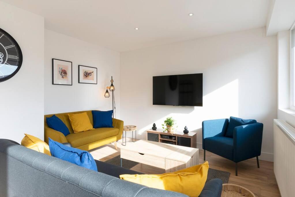 ein Wohnzimmer mit einem Sofa und zwei blauen Stühlen in der Unterkunft Le rayonnant du Placieux avec parking privé in Nancy