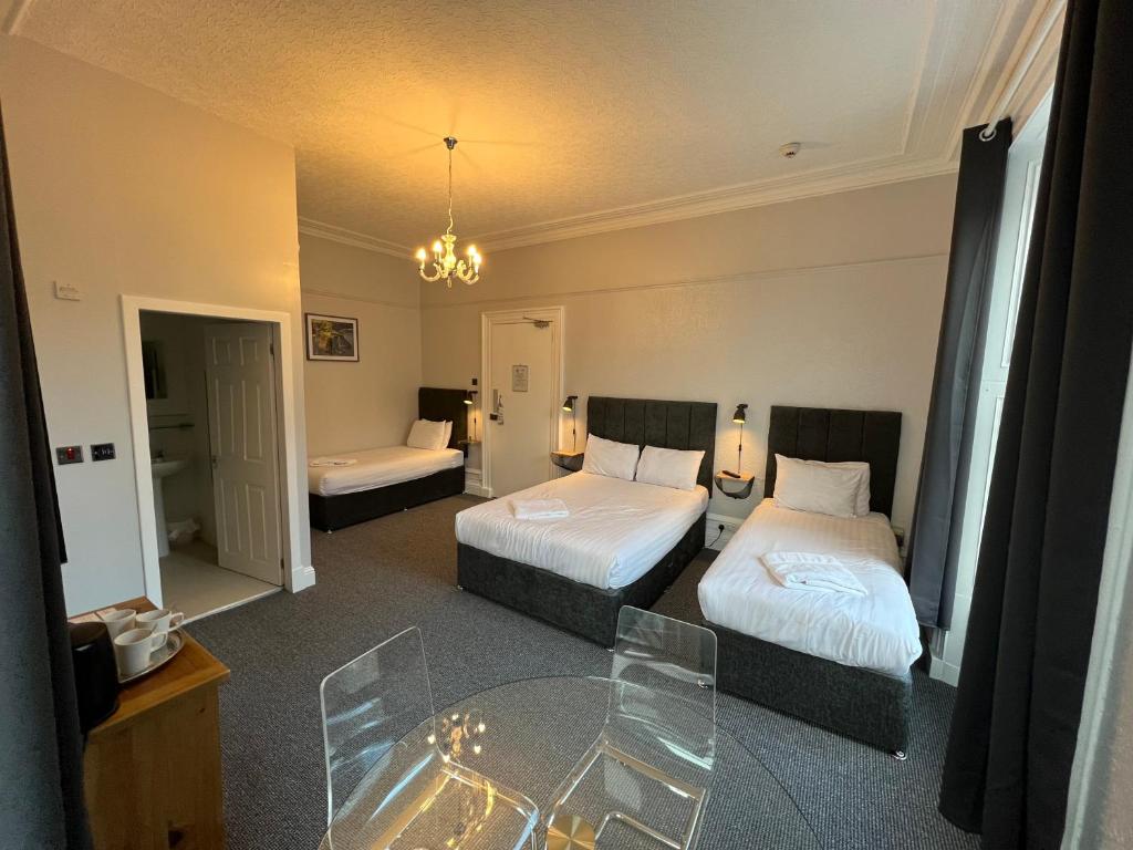 a hotel room with two beds and a glass table at Lost Guest House Aberdeen in Aberdeen