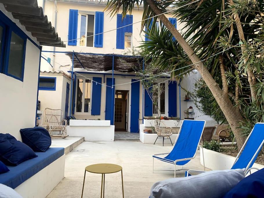 patio z niebieskimi krzesłami i stołem oraz budynek w obiekcie Villa en bord de mer à malmousque w Marsylii