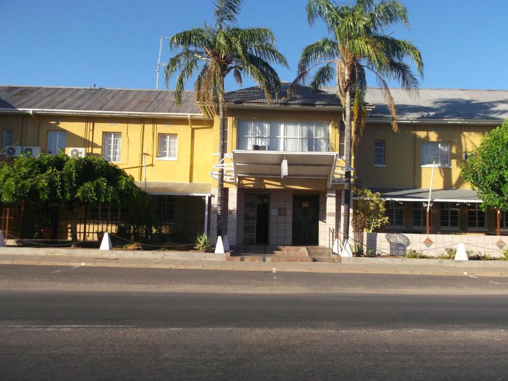 una casa gialla con palme di fronte di Keimoes Hotel a Keimoes