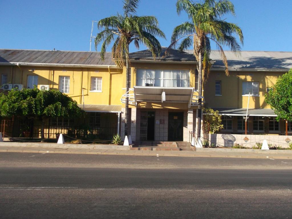 a yellow house with palm trees in front of it at Keimoes Hotel in Keimoes