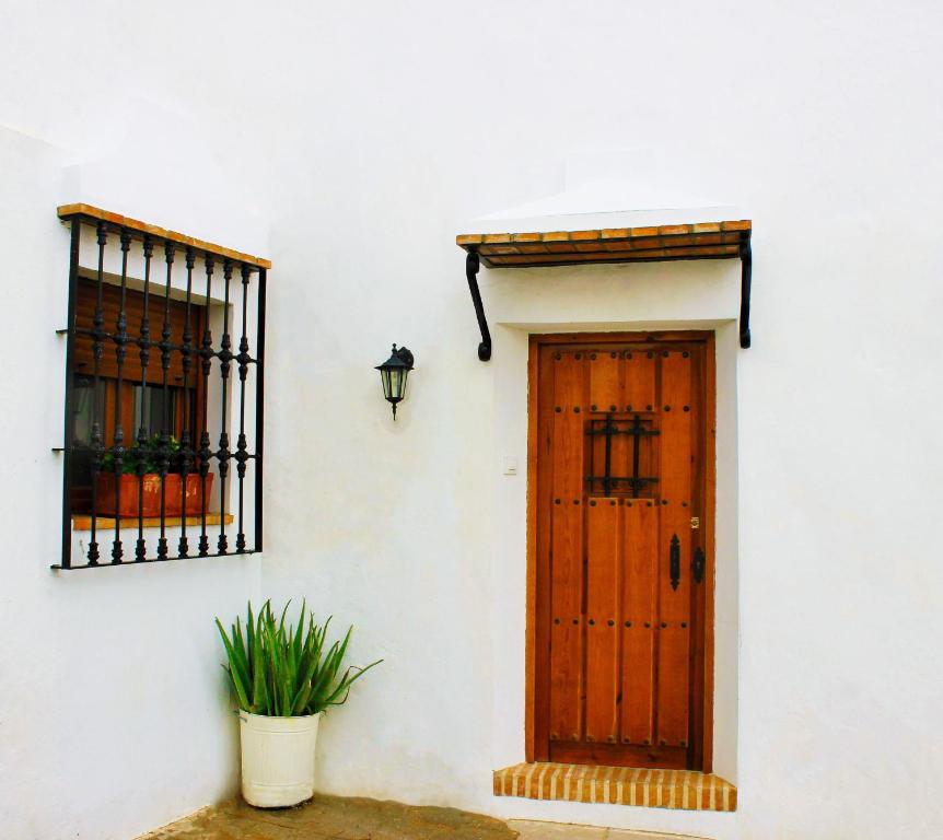 un edificio blanco con puerta de madera y ventana en Casa Pangea en Vejer de la Frontera