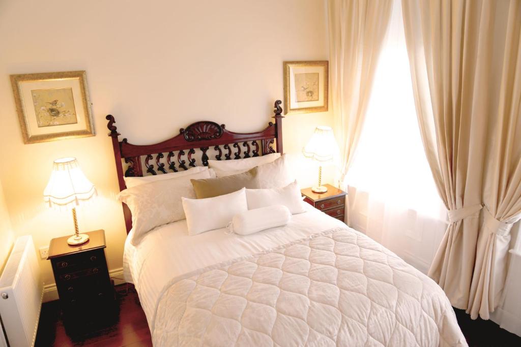 a bedroom with a large white bed with two lamps at Number 8 The Townhouse in Derry Londonderry