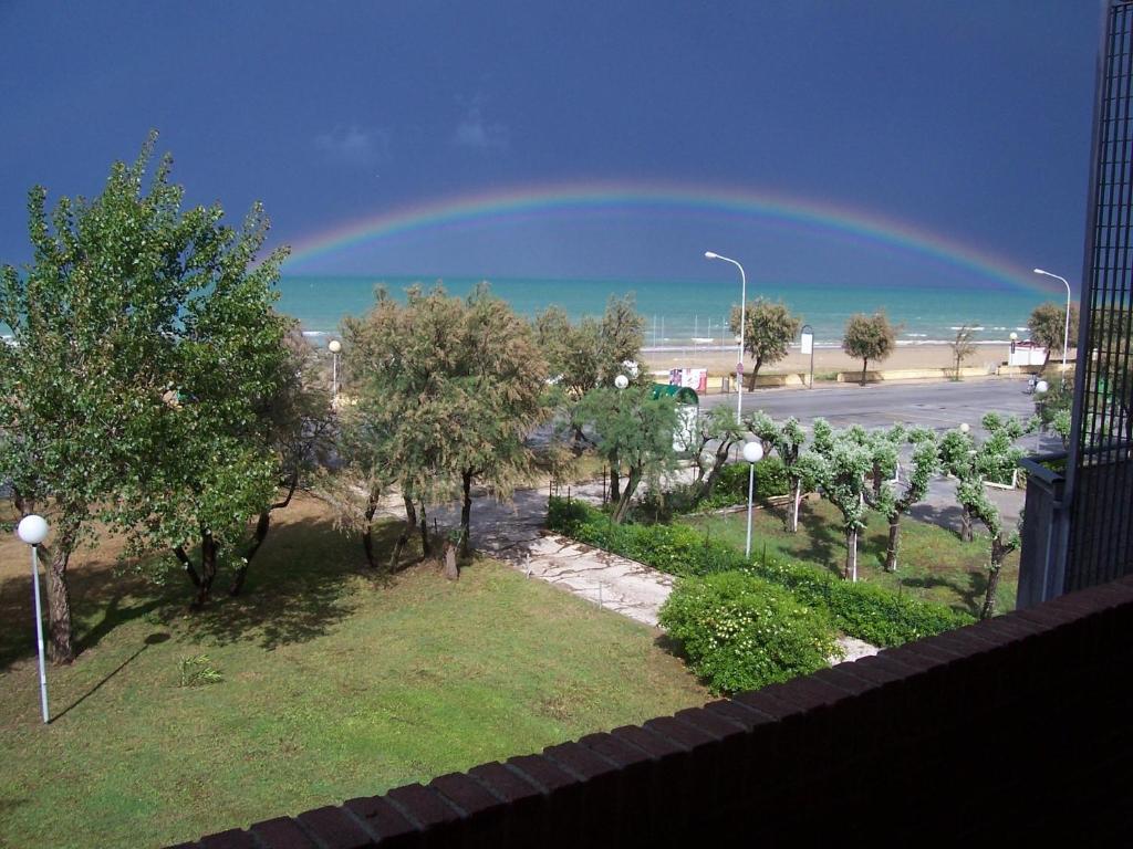 a rainbow in the sky over a street with trees at Appartamento nel Verde sul Mare di Senigallia in Senigallia