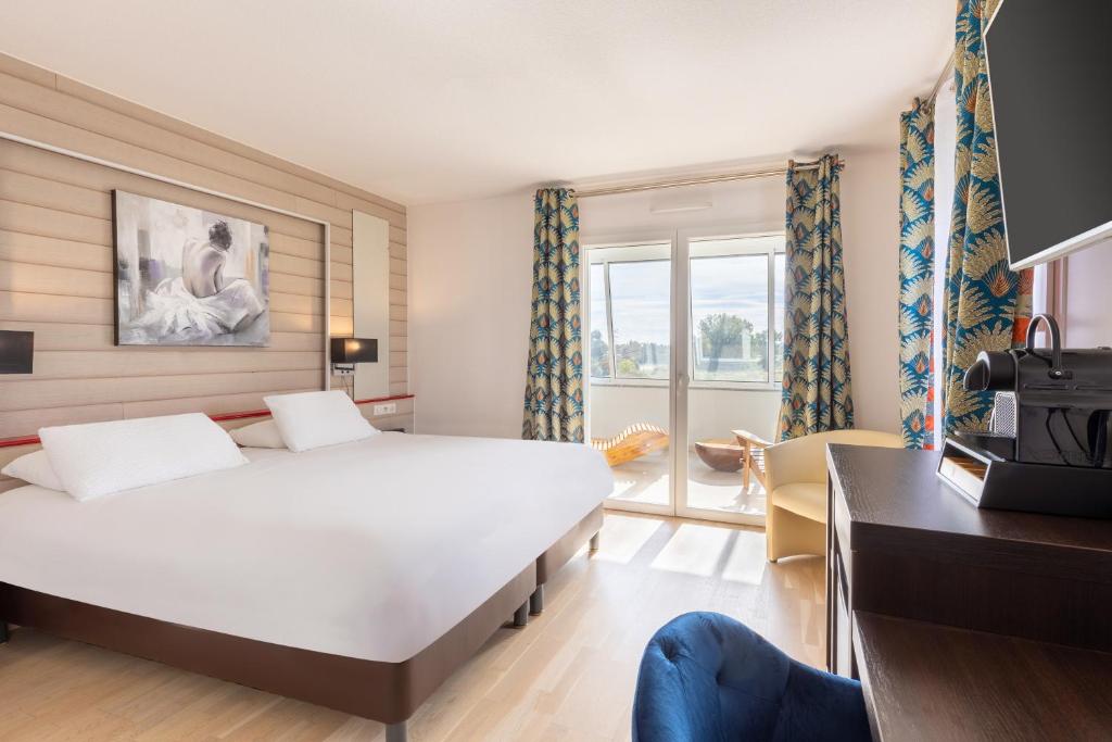 een slaapkamer met een groot wit bed en een televisie bij Best Western Hotel & SPA Pau Lescar Aeroport in Lescar