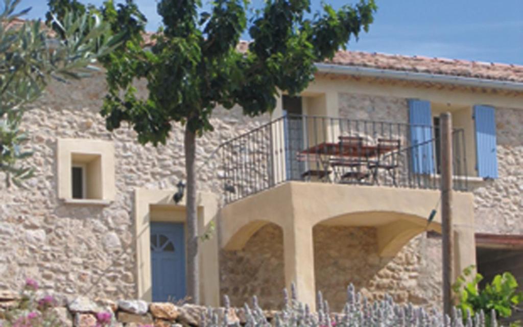une maison en pierre avec un balcon et un arbre dans l'établissement Campagne la clape g2365, à Vinon-sur-Verdon