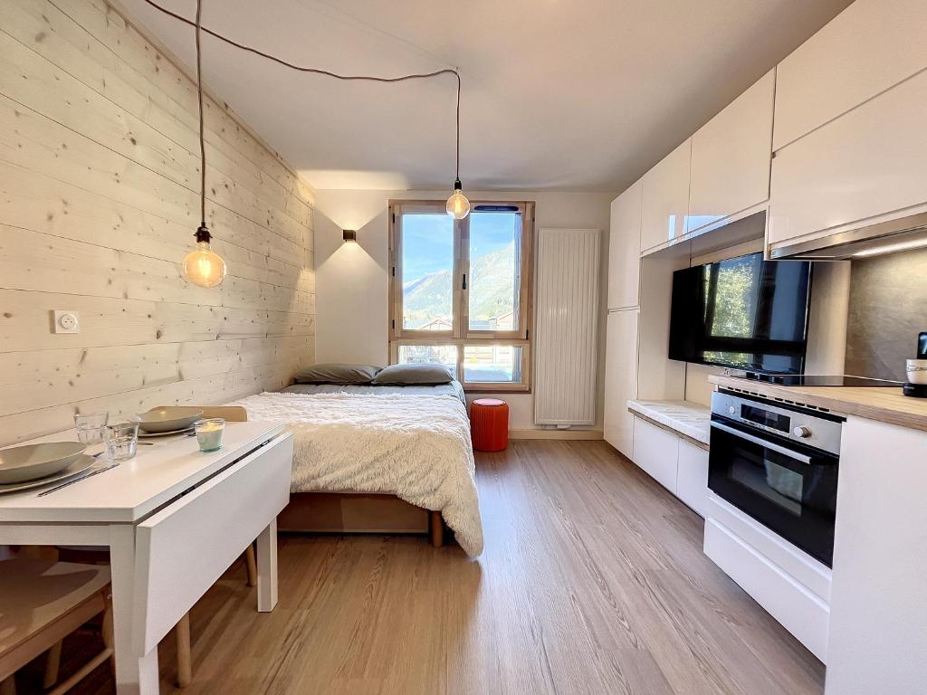 une petite chambre avec un lit et une cuisine dans l'établissement Superbe studio refait à neuf et tout équipé avec parking, à Chamonix-Mont-Blanc