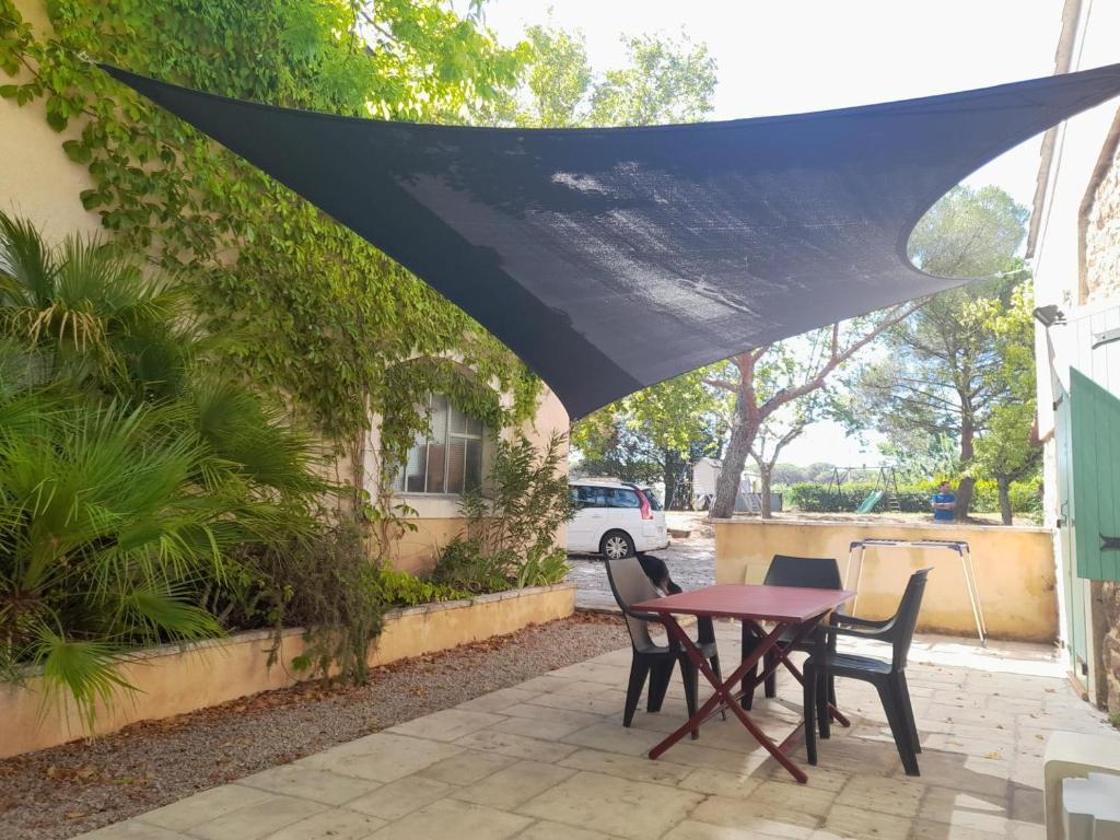 - une table et des chaises sous un parasol noir sur la terrasse dans l'établissement Le laurier aux esperifes, à Vidauban