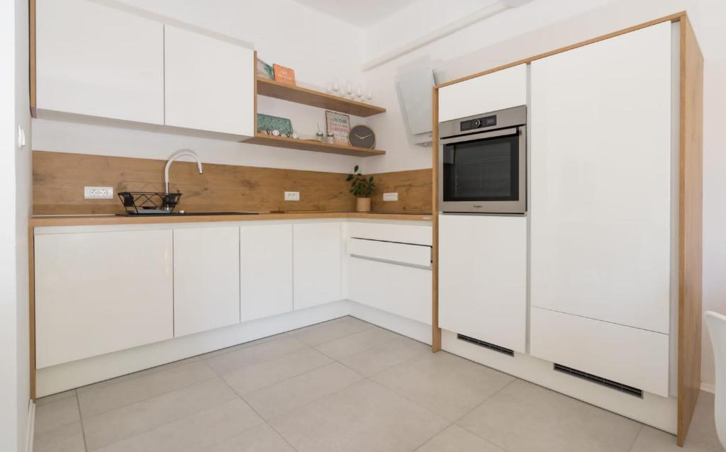 a kitchen with white cabinets and a microwave at Apartman LIS in Pomer