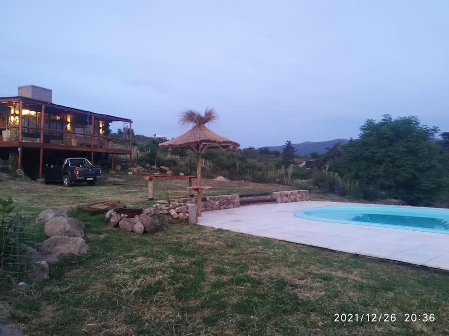 una casa con piscina y una casa con sombrilla en Cabaña LA PEDRERA - Pileta y a metros del Rio en Bialet Massé