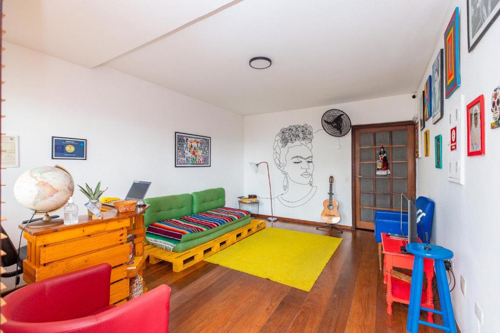 a living room with a green couch and red chairs at Hostel Casa Azul in Sao Paulo