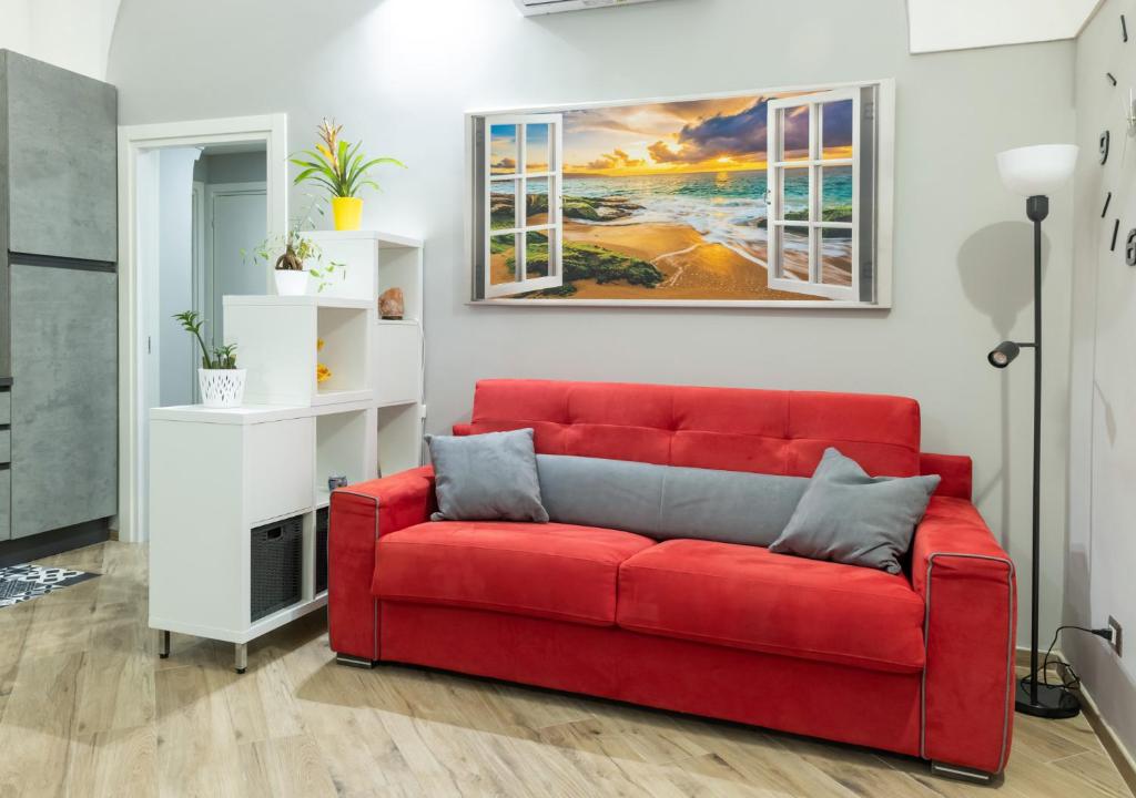 un sofá rojo en una sala de estar con una pintura en La casa del Pumo en Brindisi