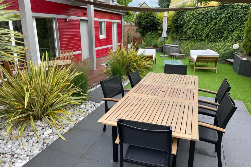 a patio with a wooden table and chairs at Nice house with pool near the city center in Hérouville-Saint-Clair