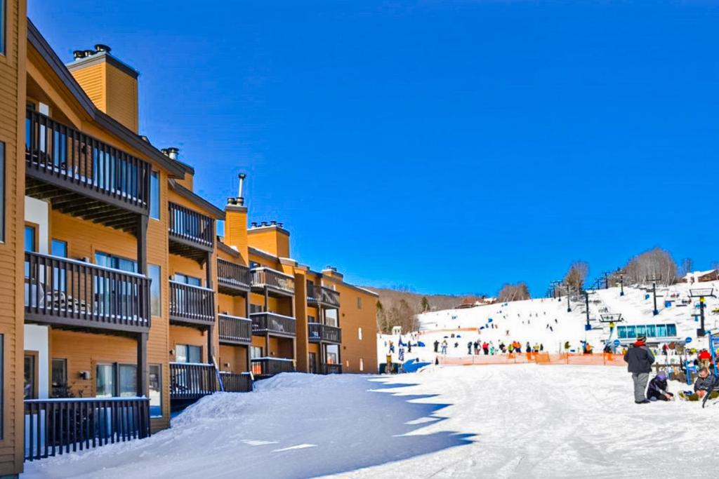 una calle cubierta de nieve frente a una estación de esquí en Okemo Mountain Lodge B203, en Ludlow