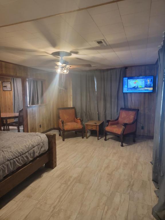 - une chambre avec deux chaises, un lit et une télévision dans l'établissement Daves shallow lake lodge at reelfoot lake, à Samburg