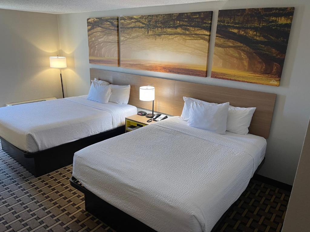 Una habitación de hotel con dos camas y un cuadro en la pared. en Days Inn by Wyndham Fayetteville-South&#47;I-95 Exit 49, en Fayetteville