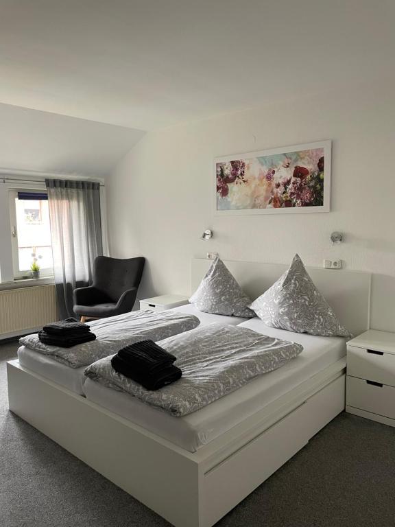 a white bedroom with a bed and a chair at Zum Deutschen Heinrich in Gifhorn