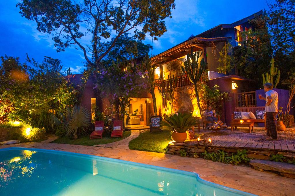a man standing in front of a house with a swimming pool at Pousada Maya in Alto Paraíso de Goiás